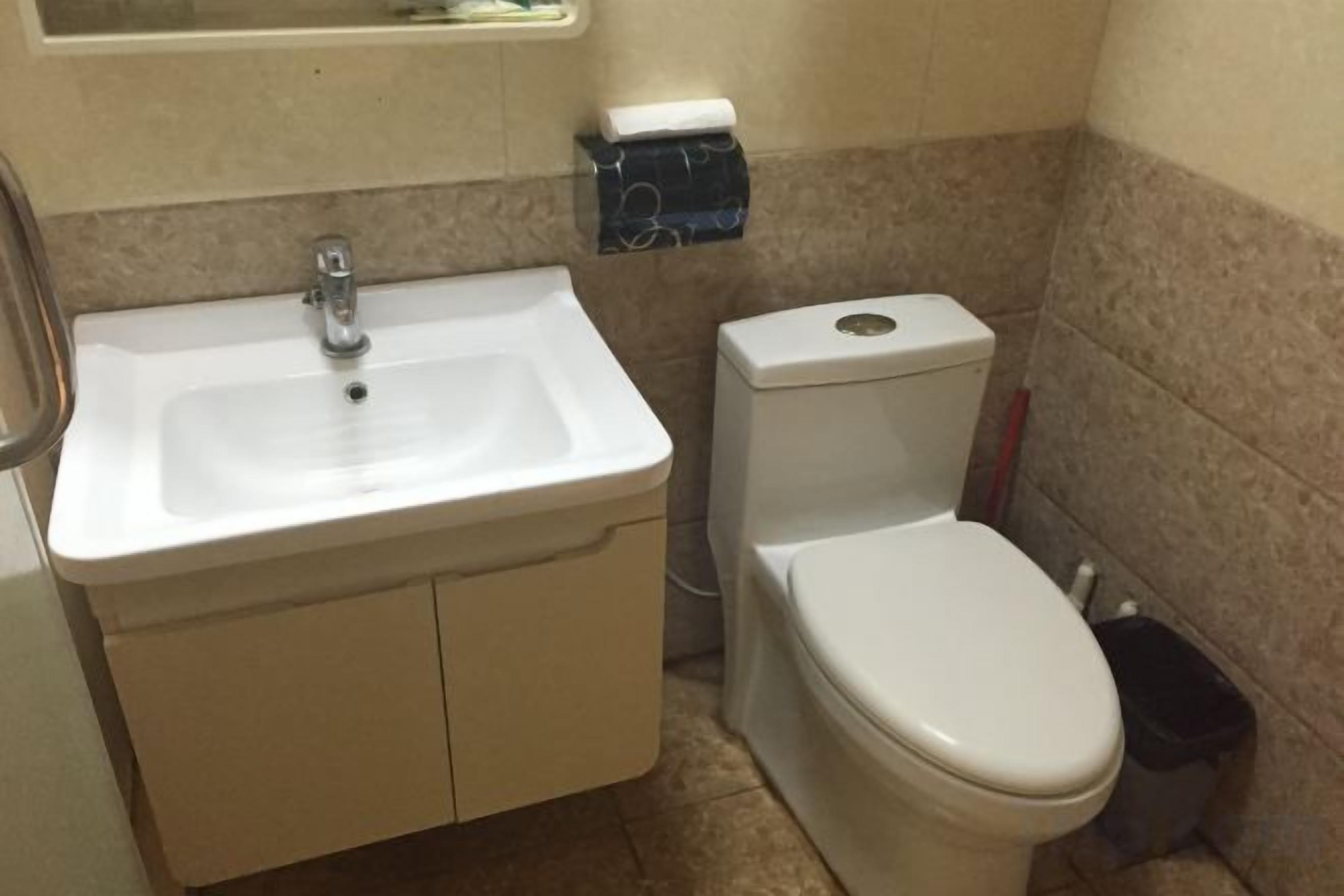 Een badkamer met een wastafel, toilet en prullenbak.