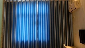 A room with a large window covered by vertical blinds, a desk with a chair, and an air conditioning unit mounted on the wall. - Qixian 168 Express Hotel (Qi County)