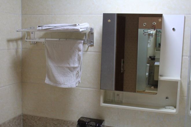 A bathroom with a towel rack, a mirror, and a toilet.