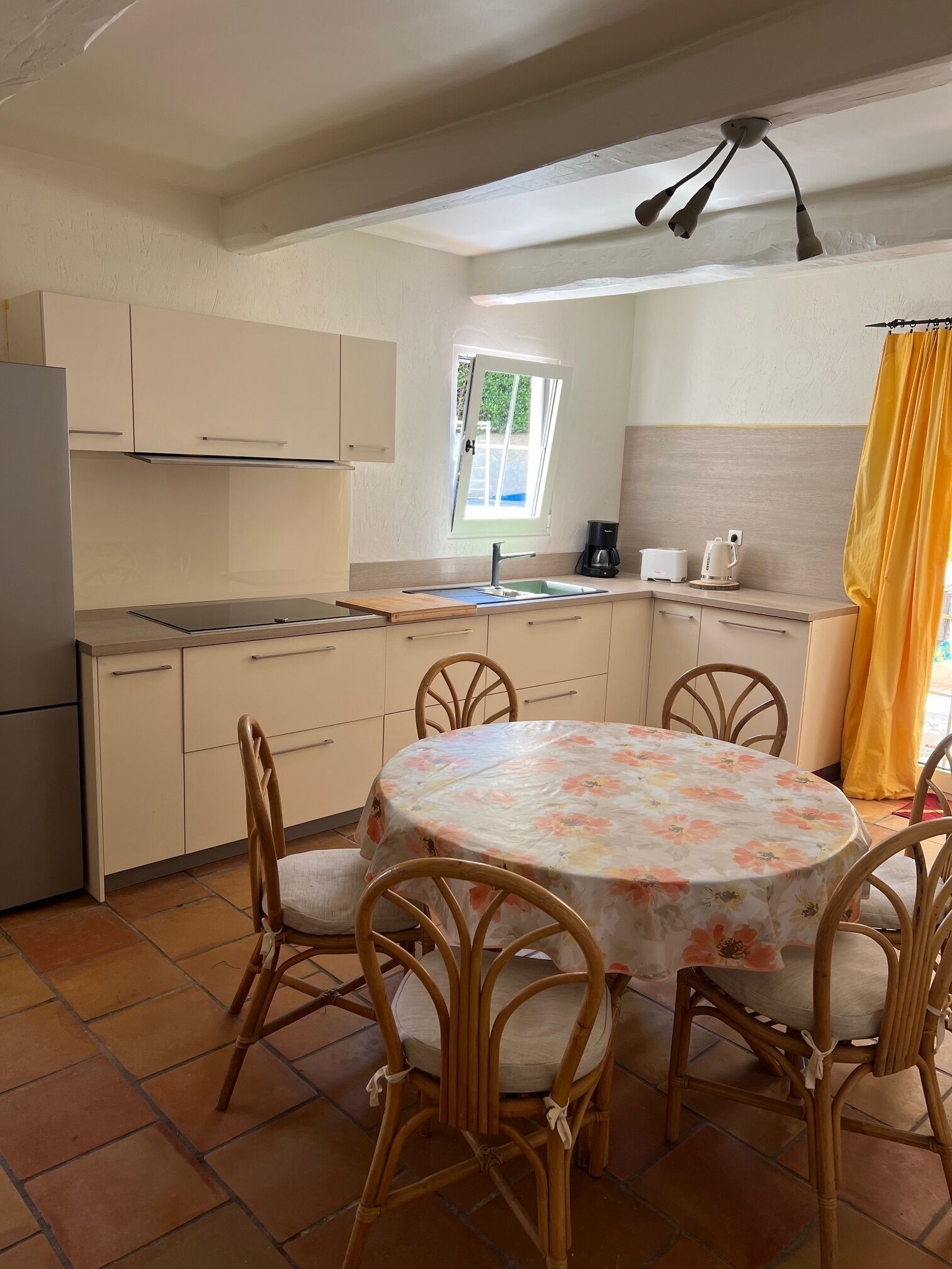 A compact kitchen with a dining area, a window, and a ceiling fan.