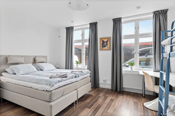 A modern bedroom with a bed, a desk, and a window with curtains. - HernöRum - Franzéngatan (Harnosand)
