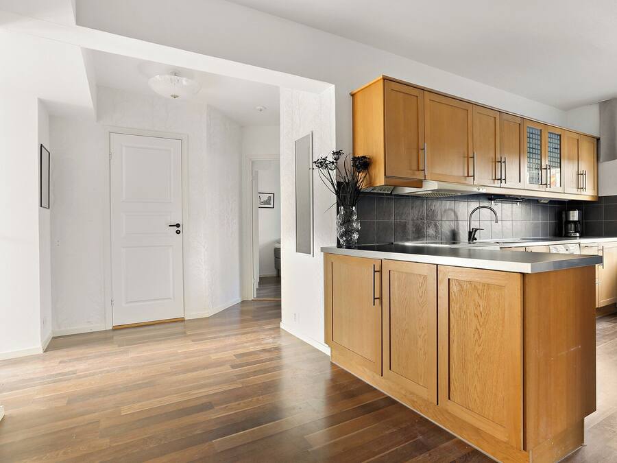 Una cocina moderna con armarios de madera, encimera negra y pileta de acero inoxidable.