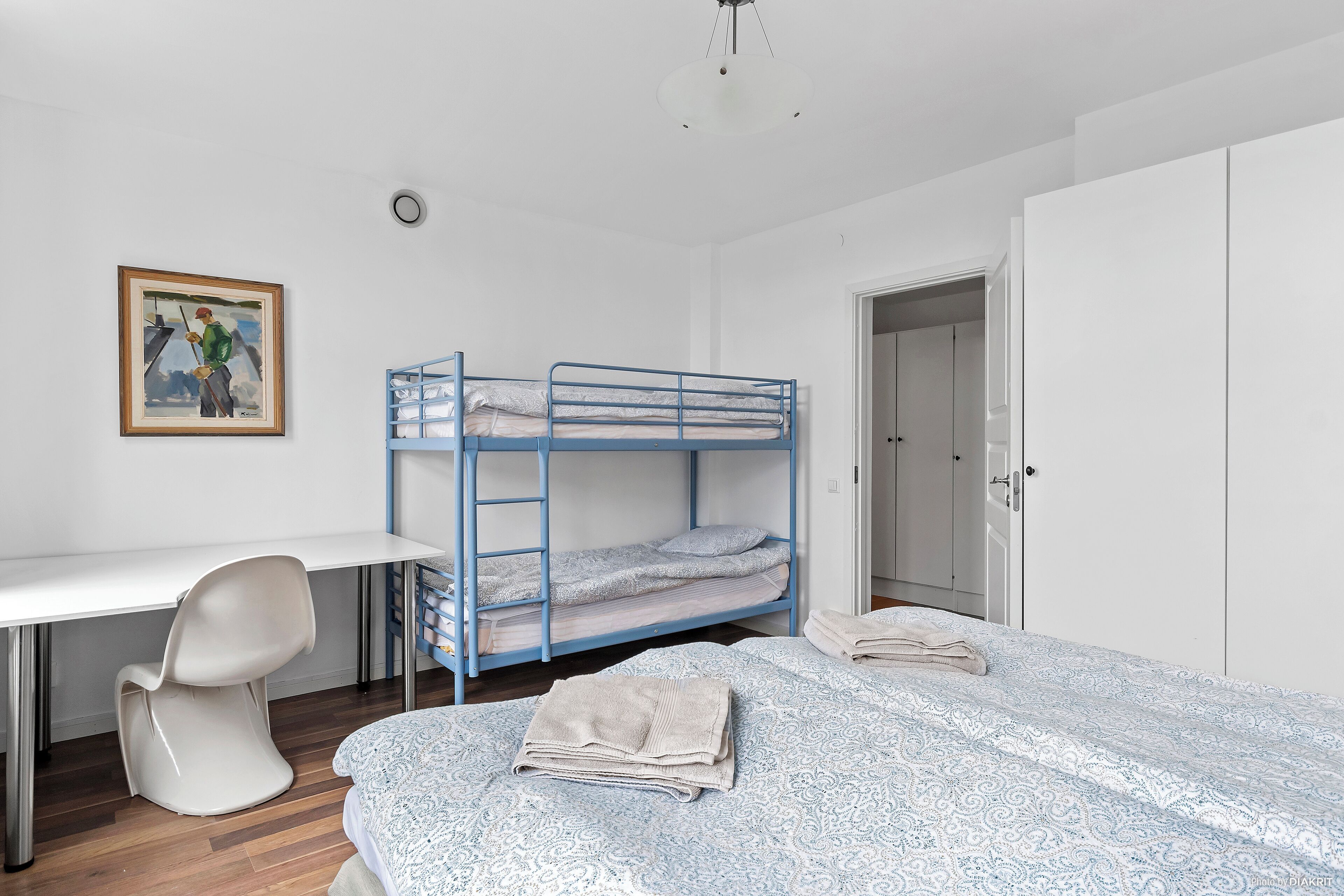 Une chambre de dortoir avec des lits superposés, un bureau, une chaise et une armoire.
