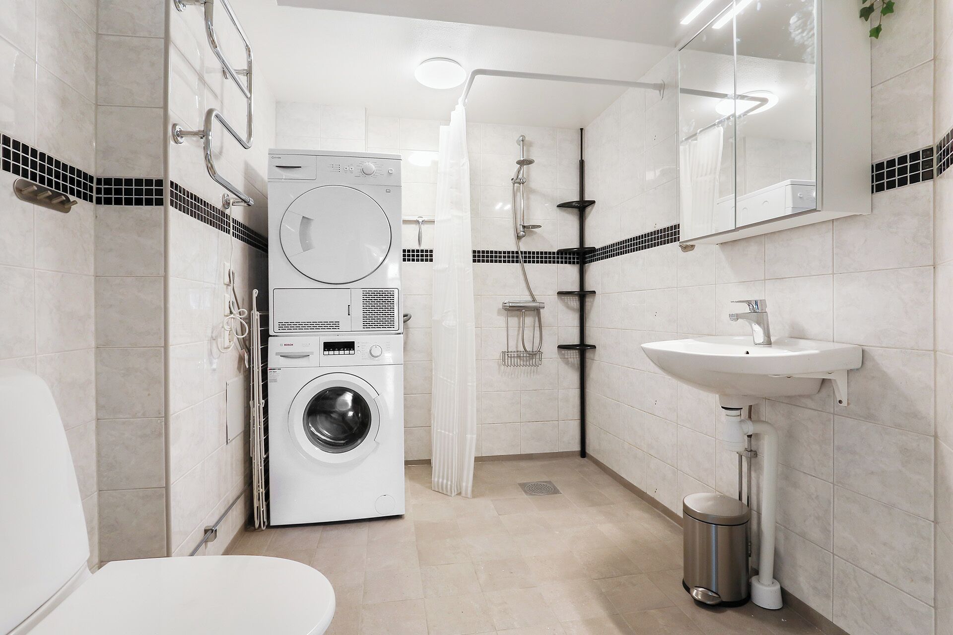 A modern bathroom with a washing machine, a shower, and a sink.