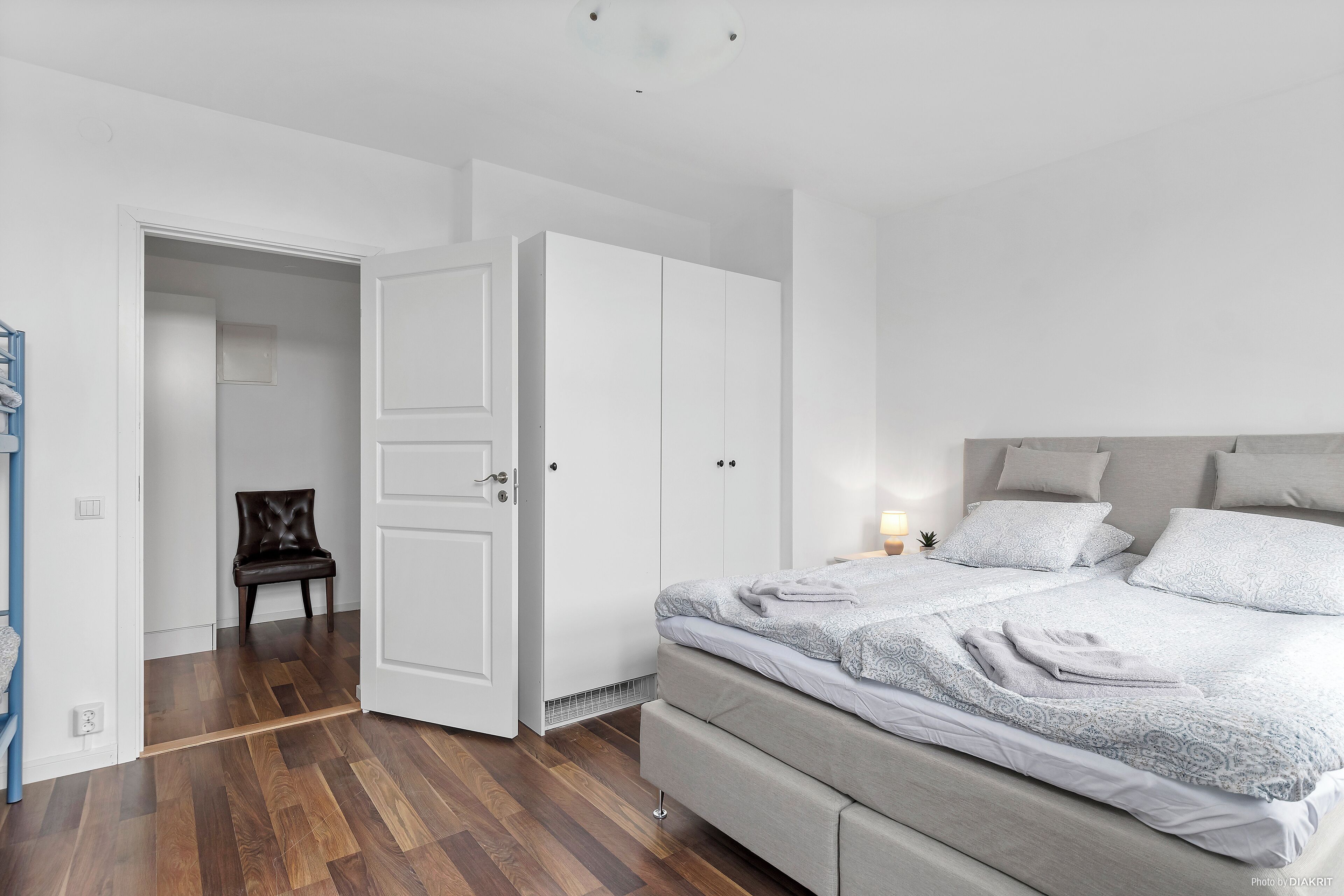 A bedroom with a bed, a wardrobe, and a chair.