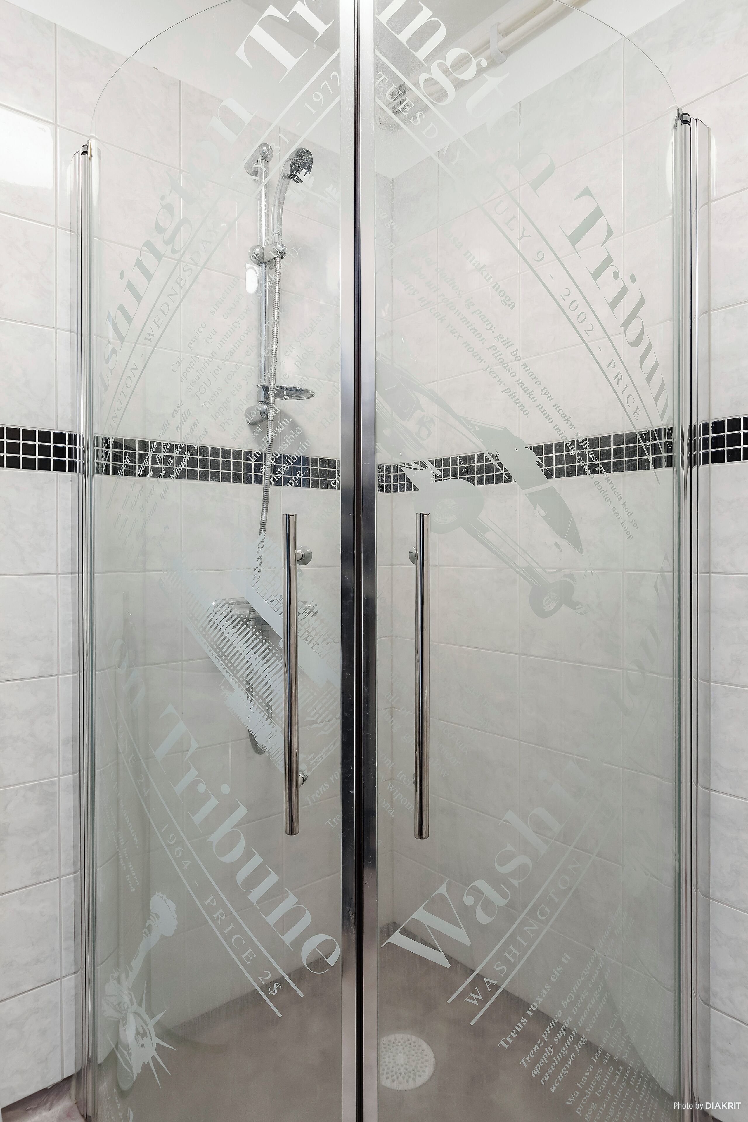 A glass-enclosed shower stall with a handheld showerhead and a vertical rain showerhead.