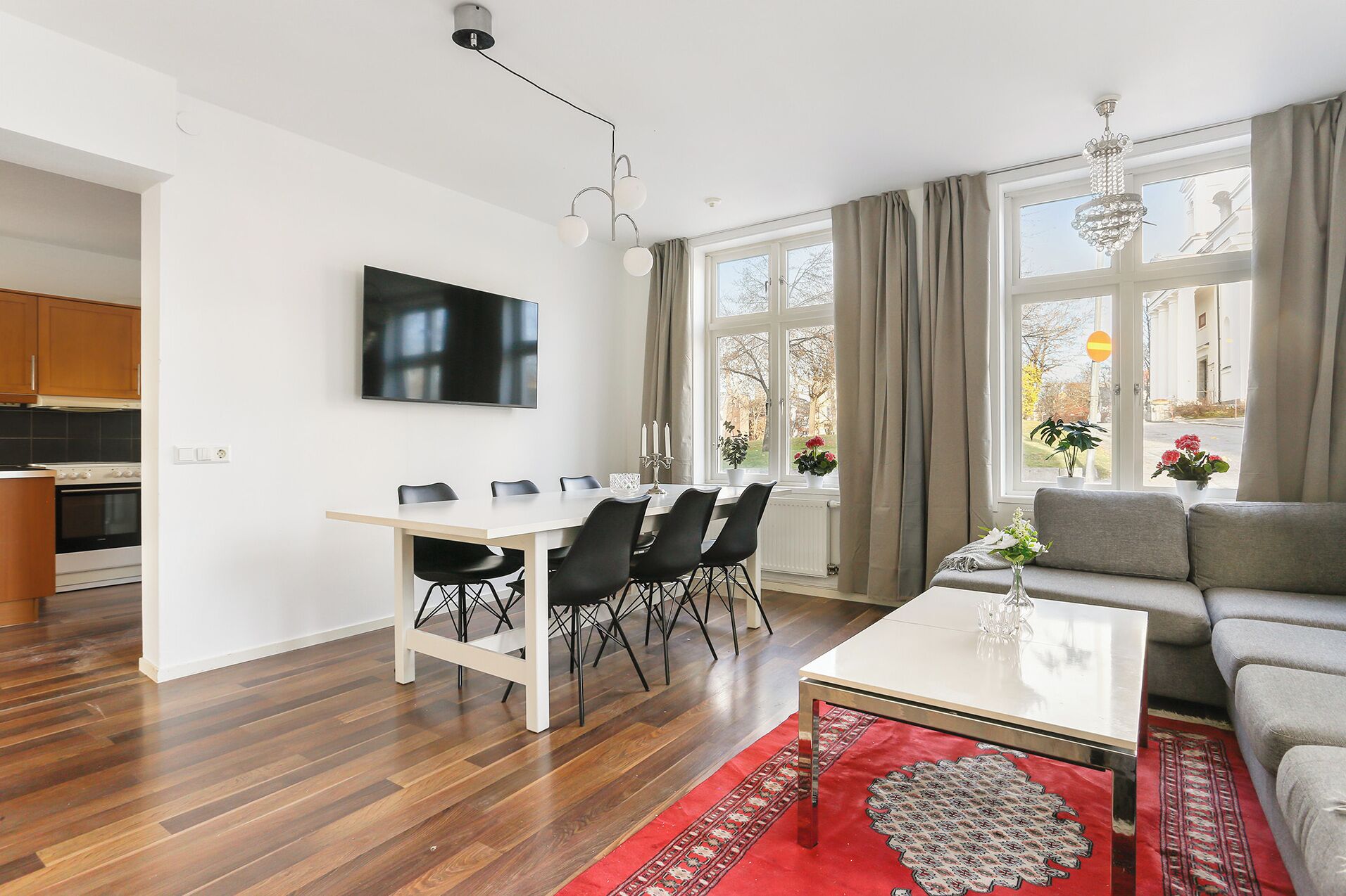 Una sala de estar moderna con comedor, cocina y un amplio ventanal con cortinas.