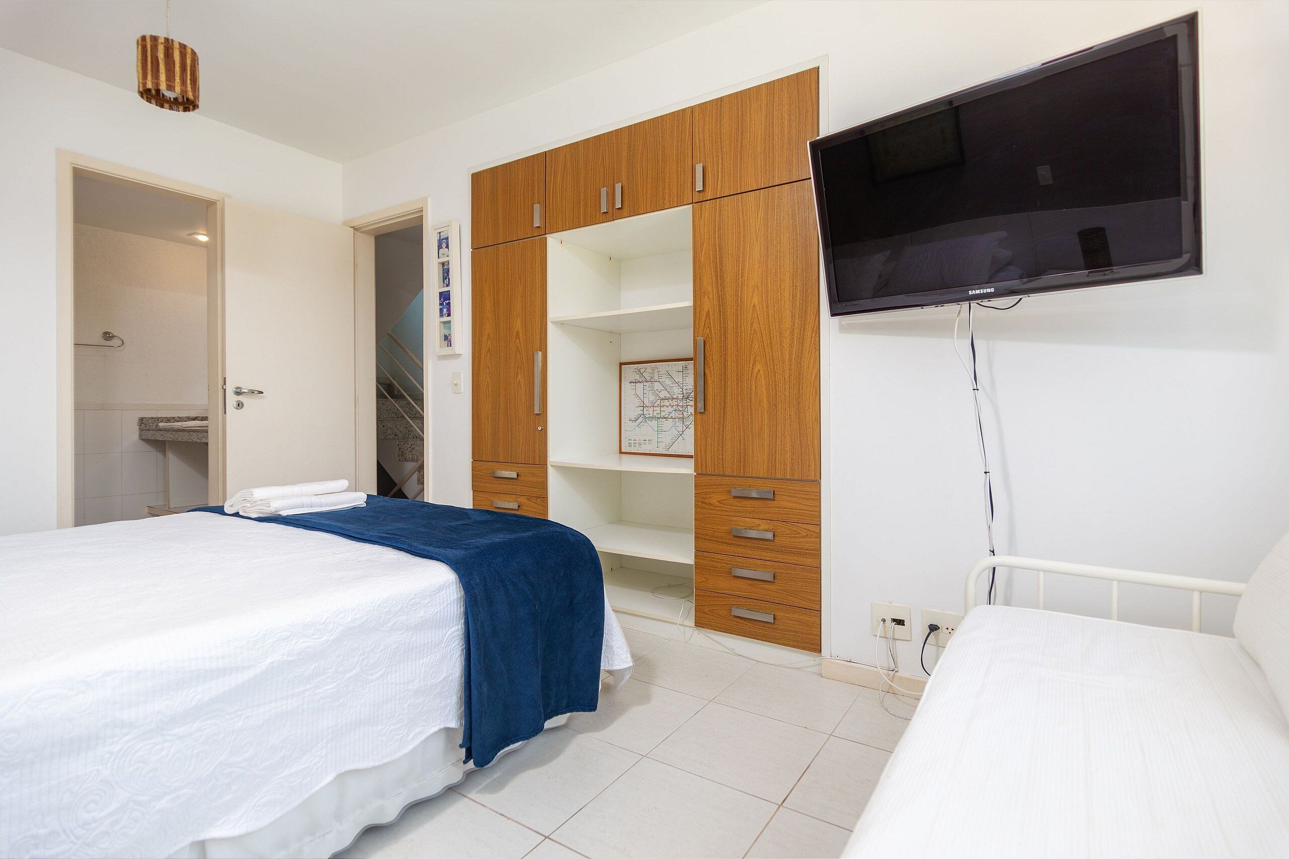 Une chambre avec deux lits, une armoire en bois, une télévision et une carte accrochée au mur.