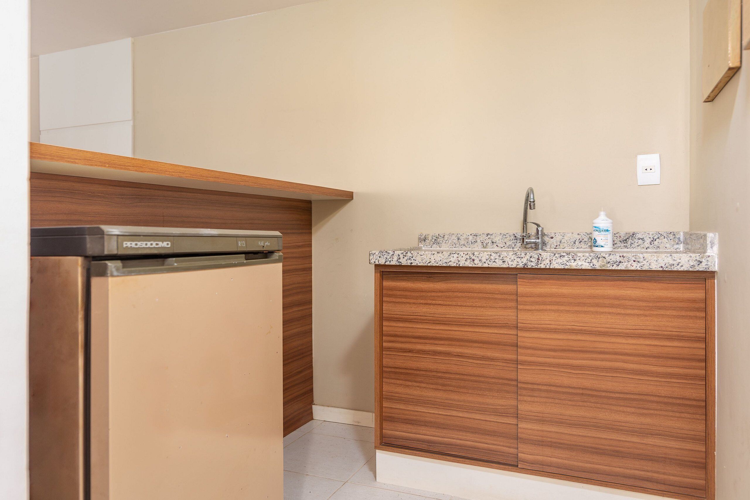 Una cocina con lavavajillas integrado, armarios de madera, encimera de granito y grifo de acero inoxidable.