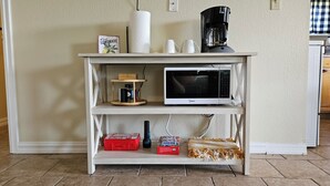 A kitchen counter with a microwave, a coffee maker, and a shelf with various items including a box of tissues and a container of sugar. - Heart of Disney House - Easy Trail Access (Disney)
