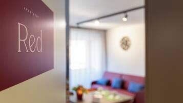 Ein verschwommener Innenraum einer Wohnung, auf einer Wand ist ein Schild mit der Aufschrift 'Apartment Red' zu sehen.