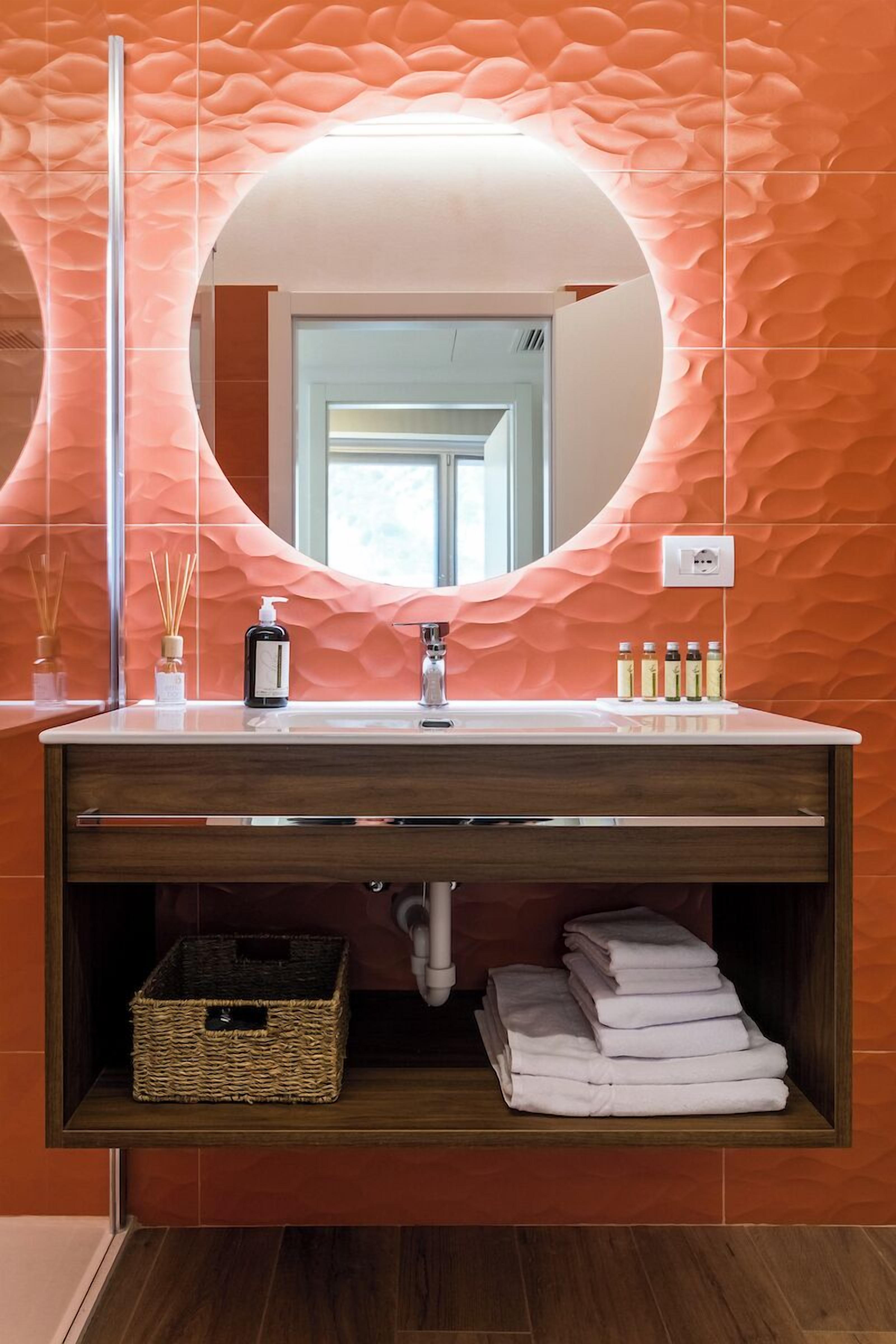 Ein modernes Badezimmer mit einem runden Spiegel, einem weißen Waschbecken und einer Holzausstattung.