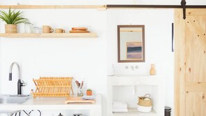 Une cuisine moderne équipée d’un évier, d’une cuisinière et d’un grille-pain. On trouve des étagères en bois au-dessus de l’évier et une étagère en bois en dessous.