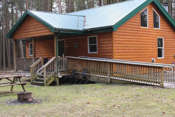 A log cabin with a porch, a wheelchair-accessible ramp, and a fire pit. - Handicap Cabin with hot tub ~ NO PETS (Clarington)