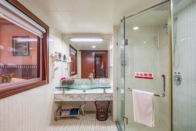 Un baño con ducha de vidrio, lavamanos de mármol y un perchero para toallas.