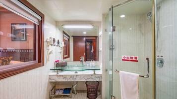 Un baño con ducha de vidrio, lavamanos de mármol y un perchero para toallas.