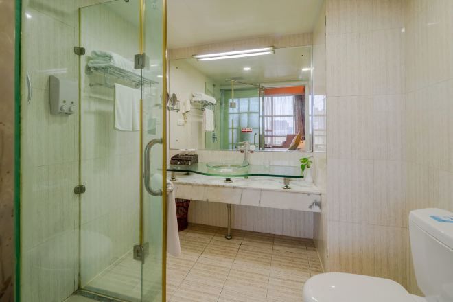 Un baño con cabina de ducha de vidrio, lavamanos de vidrio y un inodoro.