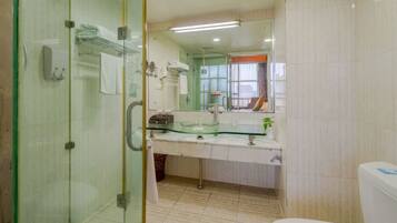 Un baño con cabina de ducha de vidrio, lavamanos de vidrio y un inodoro.