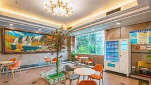 Een hotel lobby met een wanddecoratie van een waterval, een kroonluchter, een zithoek en automaten.