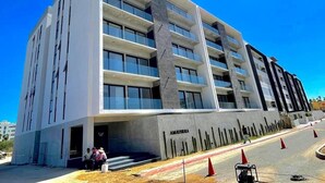 En modern byggnad med flera våningar, ett framträdande entréparti och en skylt med byggnadens namn.