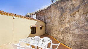 A patio with a glass table and white chairs, a tiled floor, and a wall with a satellite dish. - House Altos de Gáldar (Galdar)