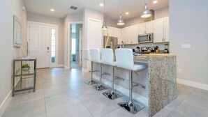 A modern kitchen with white cabinets, stainless steel appliances, and a granite island.
