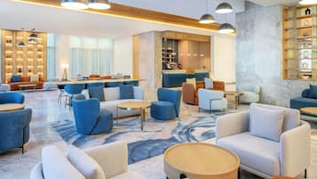 A modern hotel lobby with seating areas, a bar, and a reception desk.