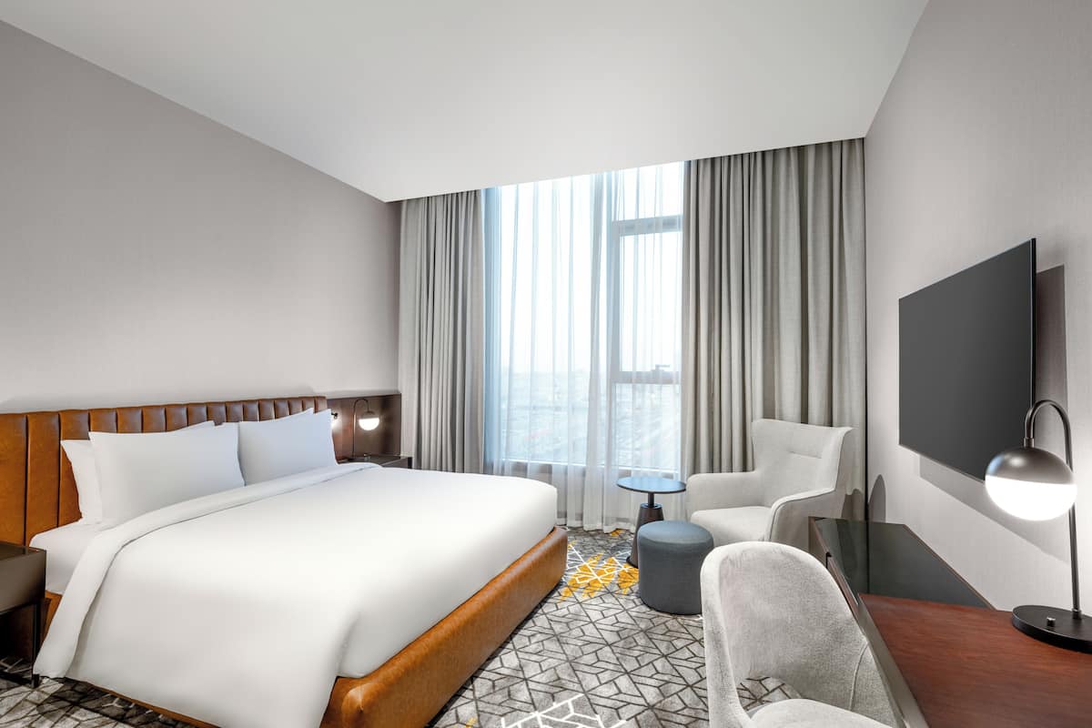 Een moderne hotelkamer met een groot bed, een bureau, een stoel en een televisie.