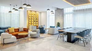 A modern living room with a sofa set, a coffee table, and a dining area with chairs and a table. - Four Points By Sheraton Jeddah King Fahd Road (Jeddah)