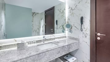 Une salle de bain avec un lavabo en marbre, une balance, un porte-serviettes et un téléphone fixé au mur.