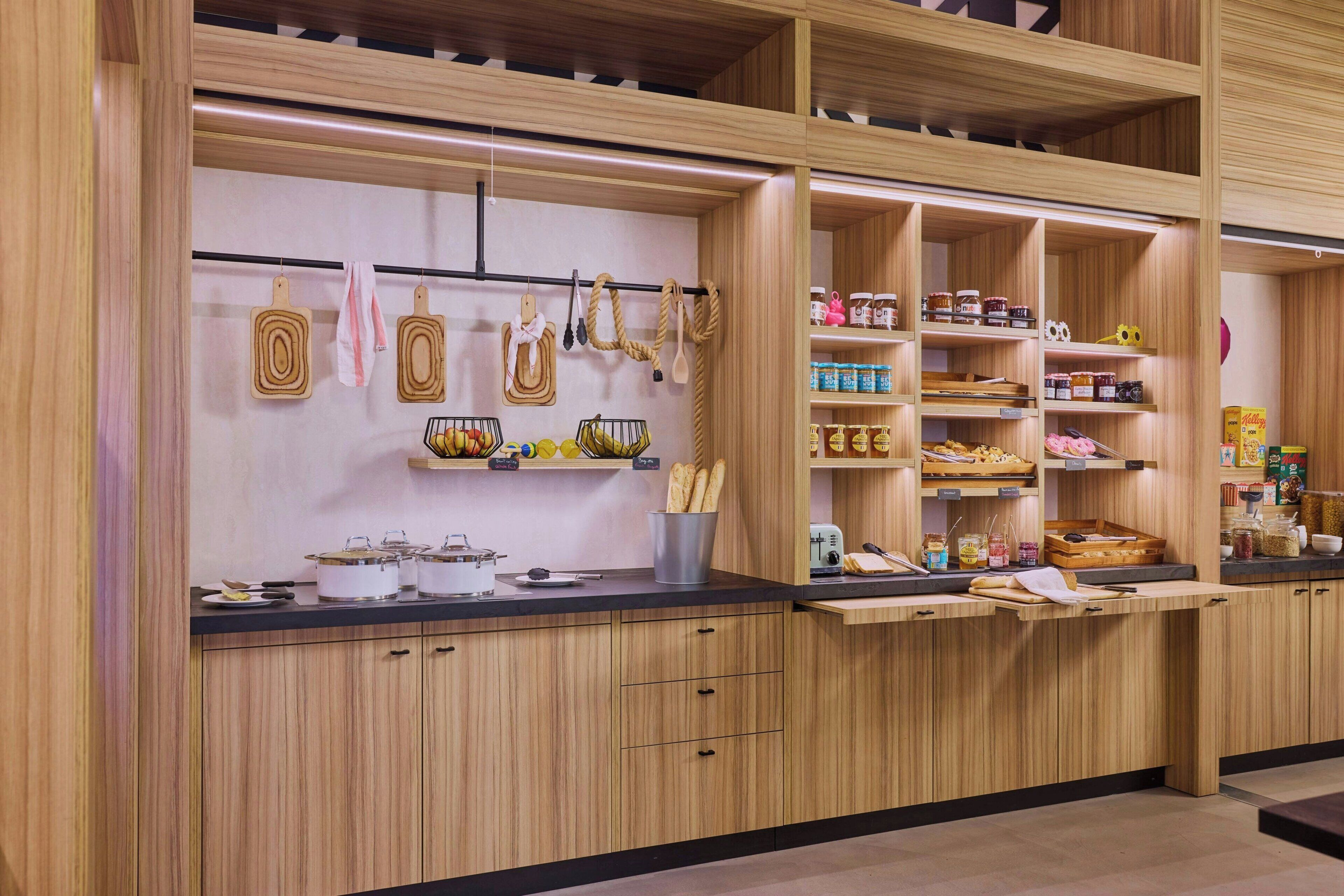 A modern kitchen with wooden cabinetry, open shelving for spices and utensils, and a black countertop.
