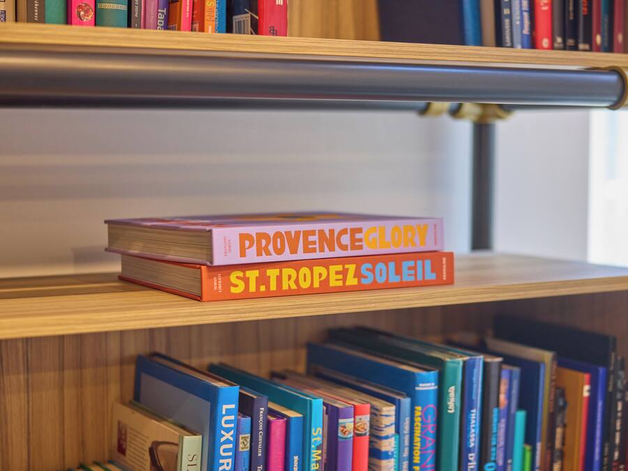 A bookshelf with books, including titles like "Provence Glory" and "St. Tropez Soleil".