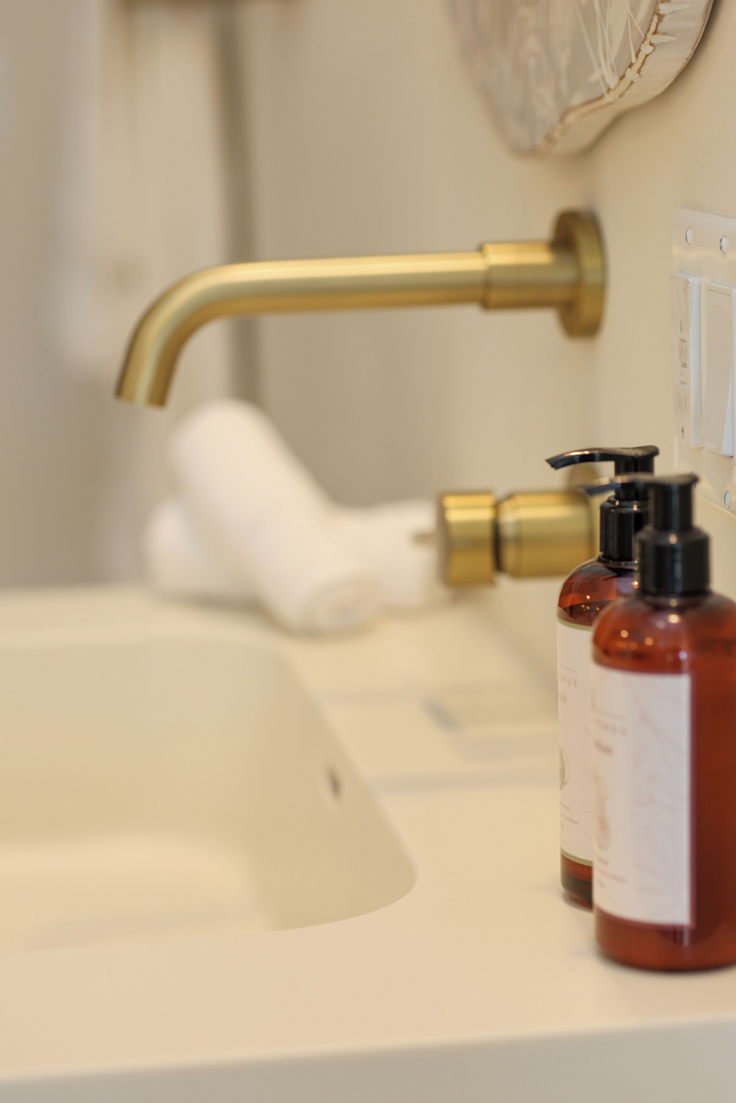 A bathroom sink with a gold faucet and two soap dispensers.