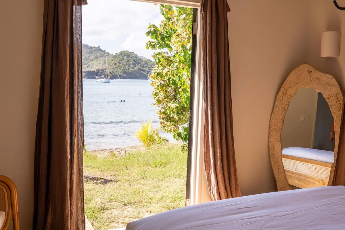 Un dormitorio con vista a un lago, una cama, un espejo y cortinas.