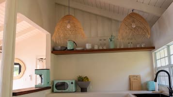 Una cucina con forno a microonde, macchina da caffè, una ciotola di frutta e lampade in vimini appese.