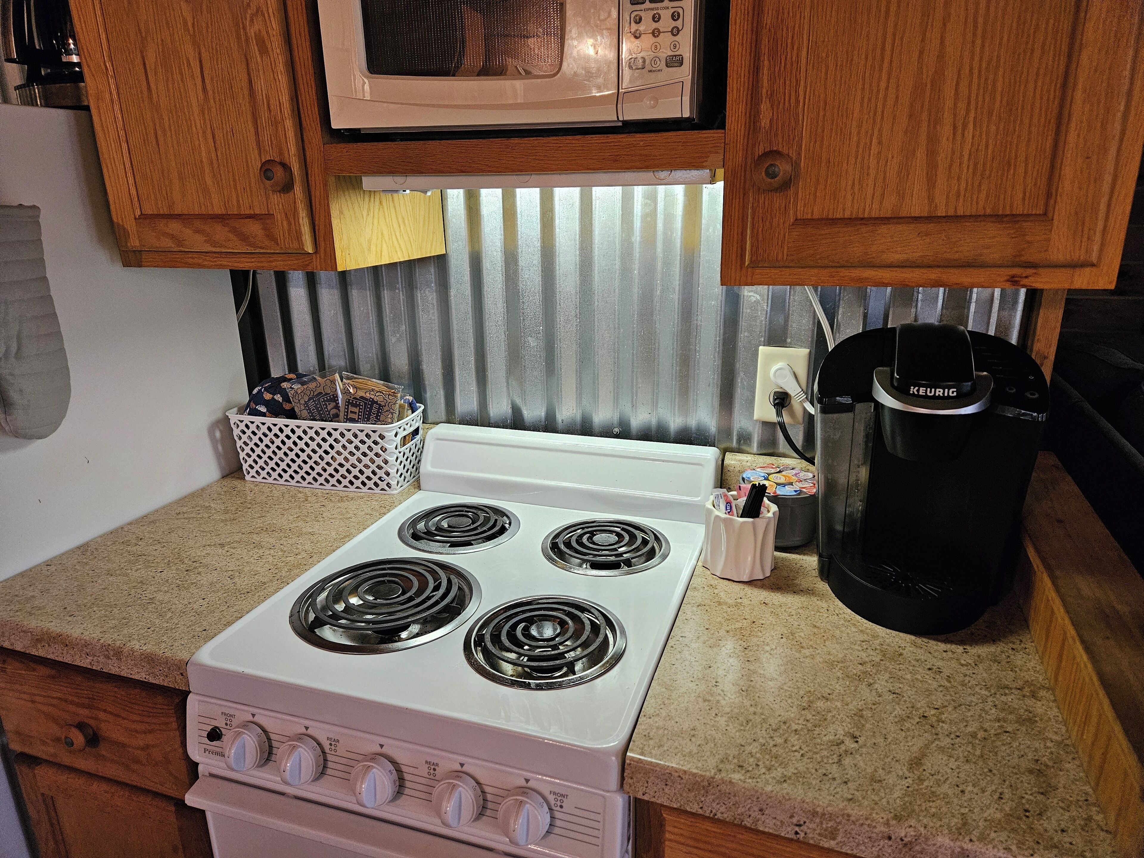 A kitchen with a white stove, a microwave above it, wooden cabinets, and a coffee maker.