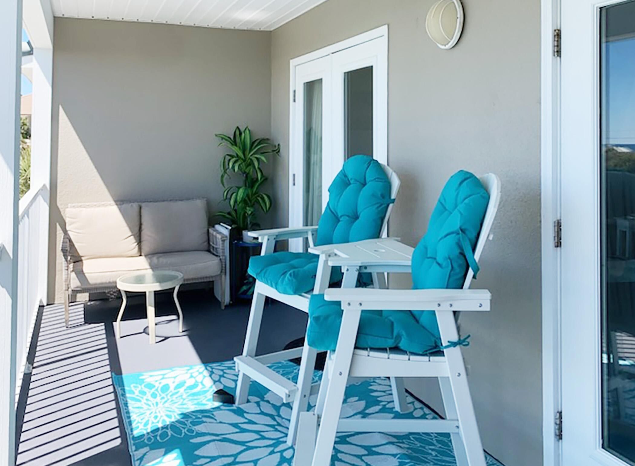 A covered outdoor seating area with a sofa and two chairs.