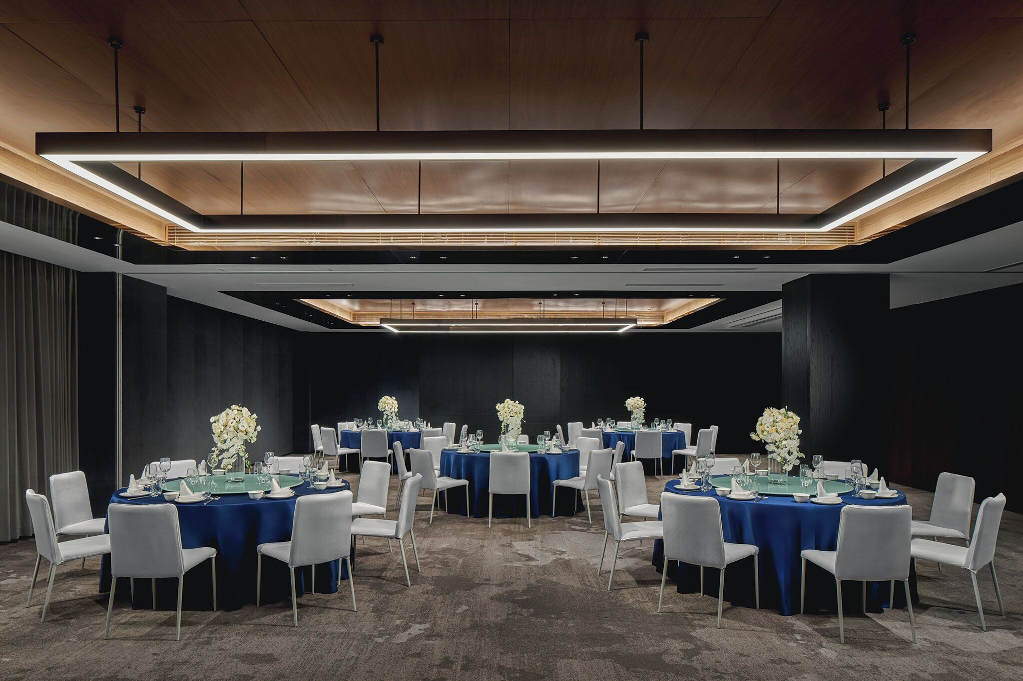 A conference room with round tables, white chairs, and blue tablecloths.