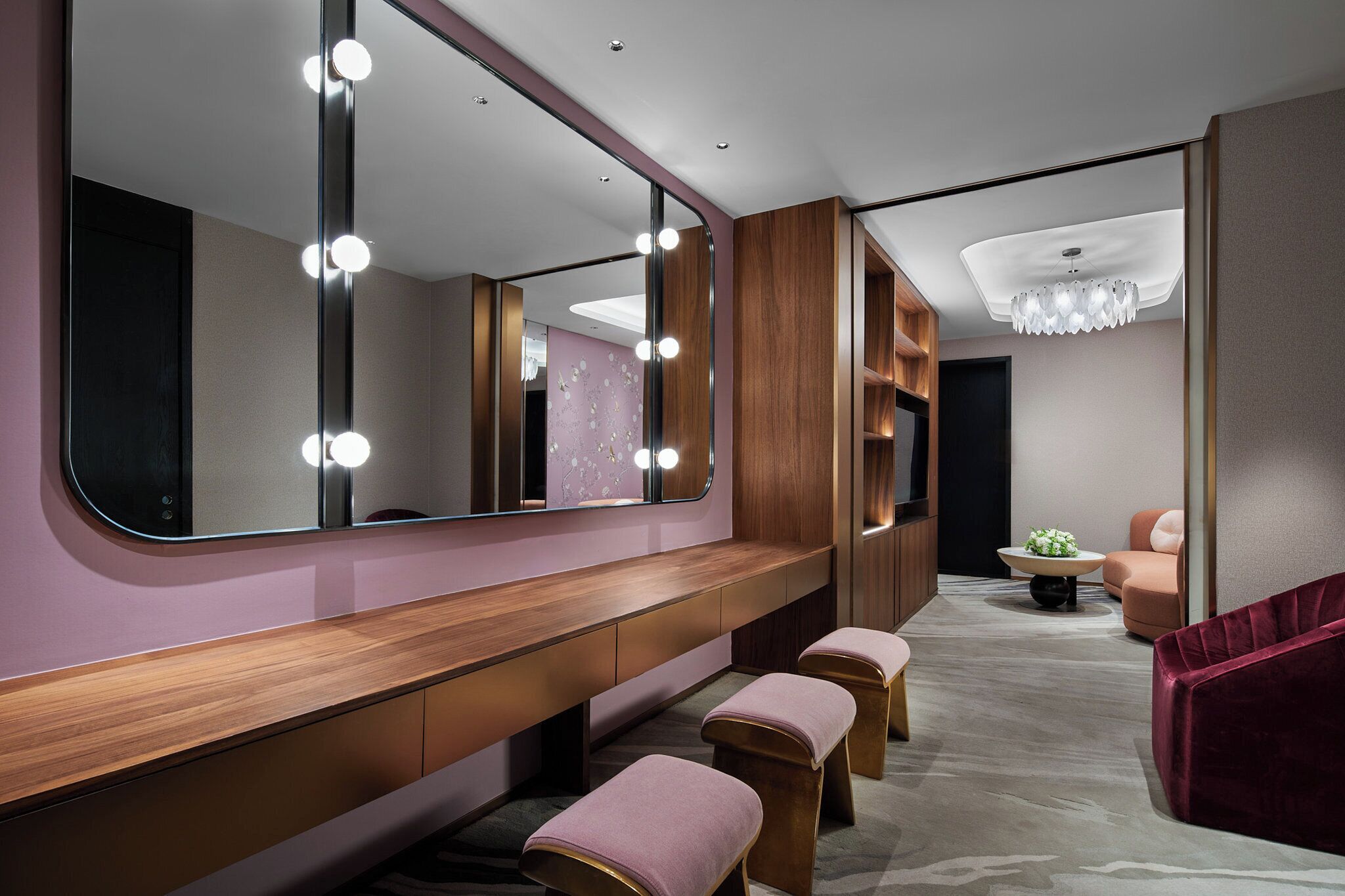 A modern bathroom with a vanity, mirrors, and seating area.
