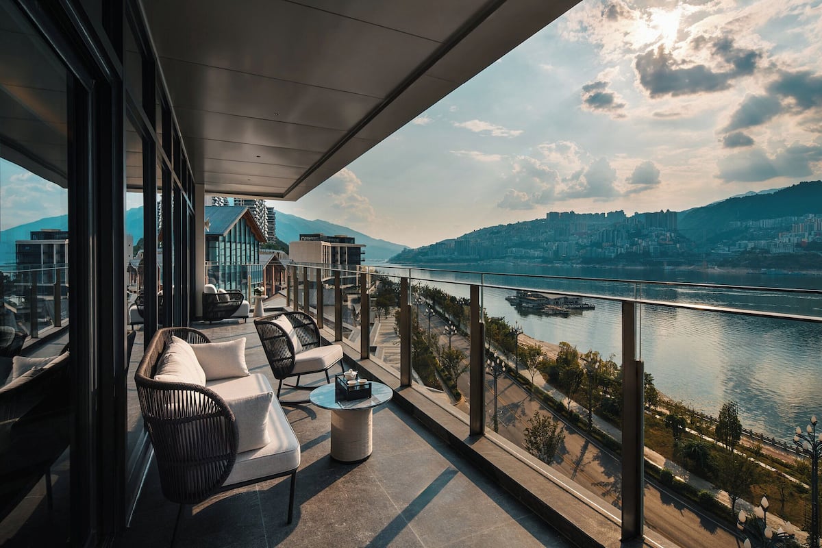 A balcony with seating and a view of a river and cityscape.