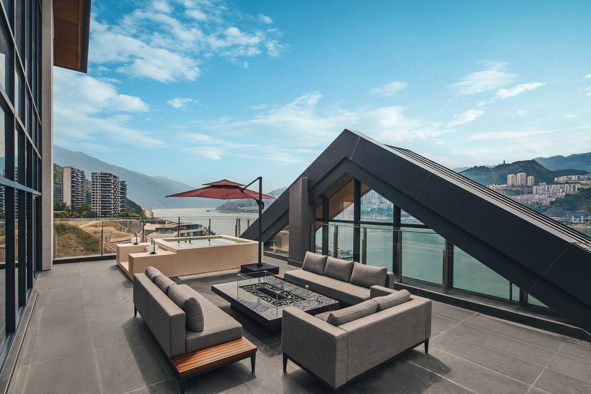 A modern outdoor lounge area with a sofa set, a coffee table, and a red umbrella.