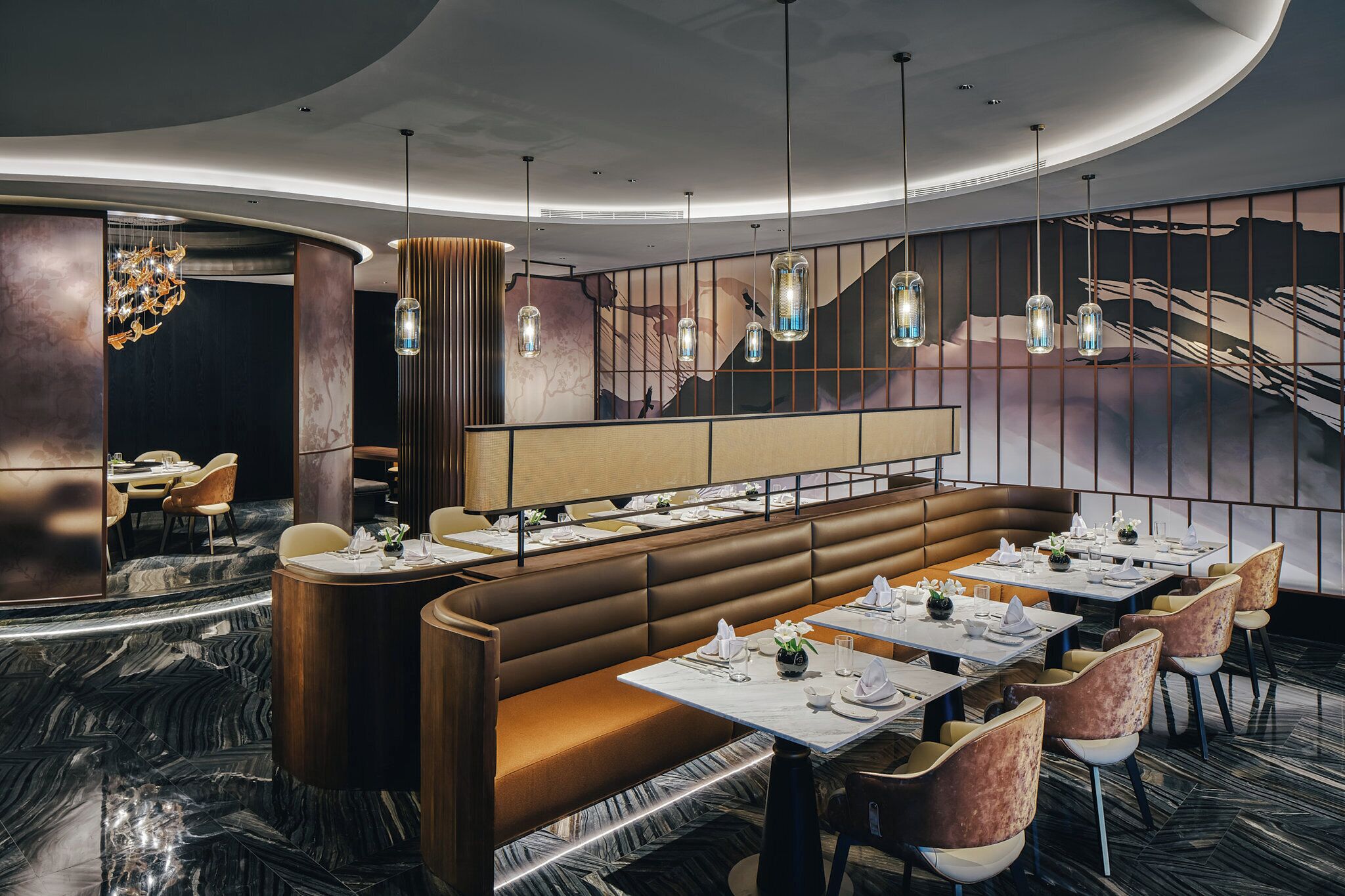 A modern restaurant with a curved ceiling, marble flooring, and a central seating area with booths and tables.