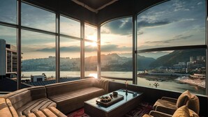 Una sala de estar moderna con un ventanal grande, un sofá, una mesa de centro y vistas a la ciudad y al río.