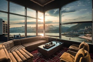 A modern living room with a large window, a sofa, a coffee table, and a view of a cityscape and river.