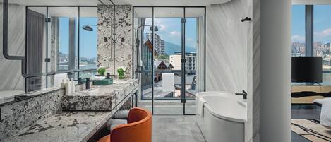 Une salle de bain moderne avec un meuble-lavabo en marbre, une baignoire et une vue sur le paysage urbain.
