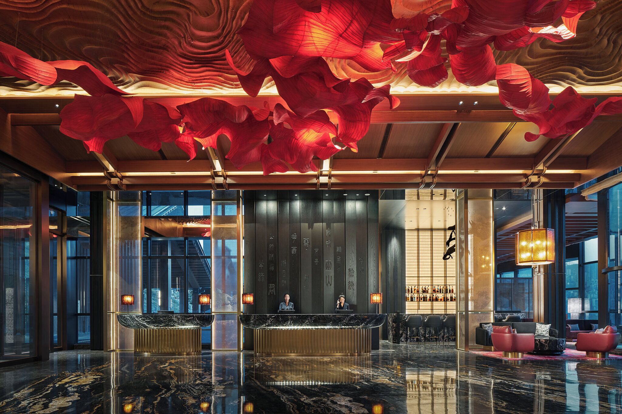 A modern lobby with a reception desk, seating area, and large windows.