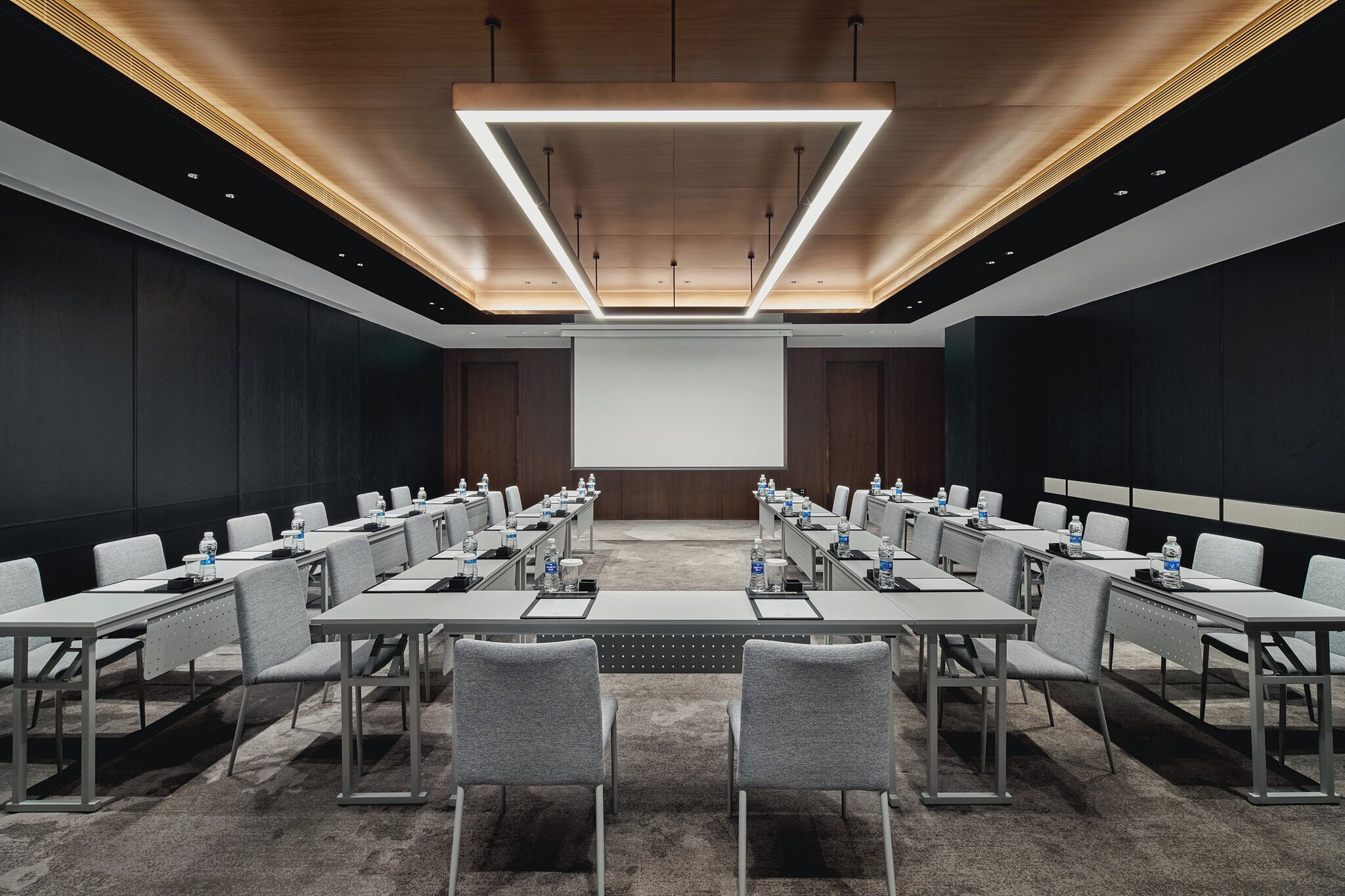 Une salle de conférence équipée d’une longue table, de nombreuses chaises et d’un écran de projection.
