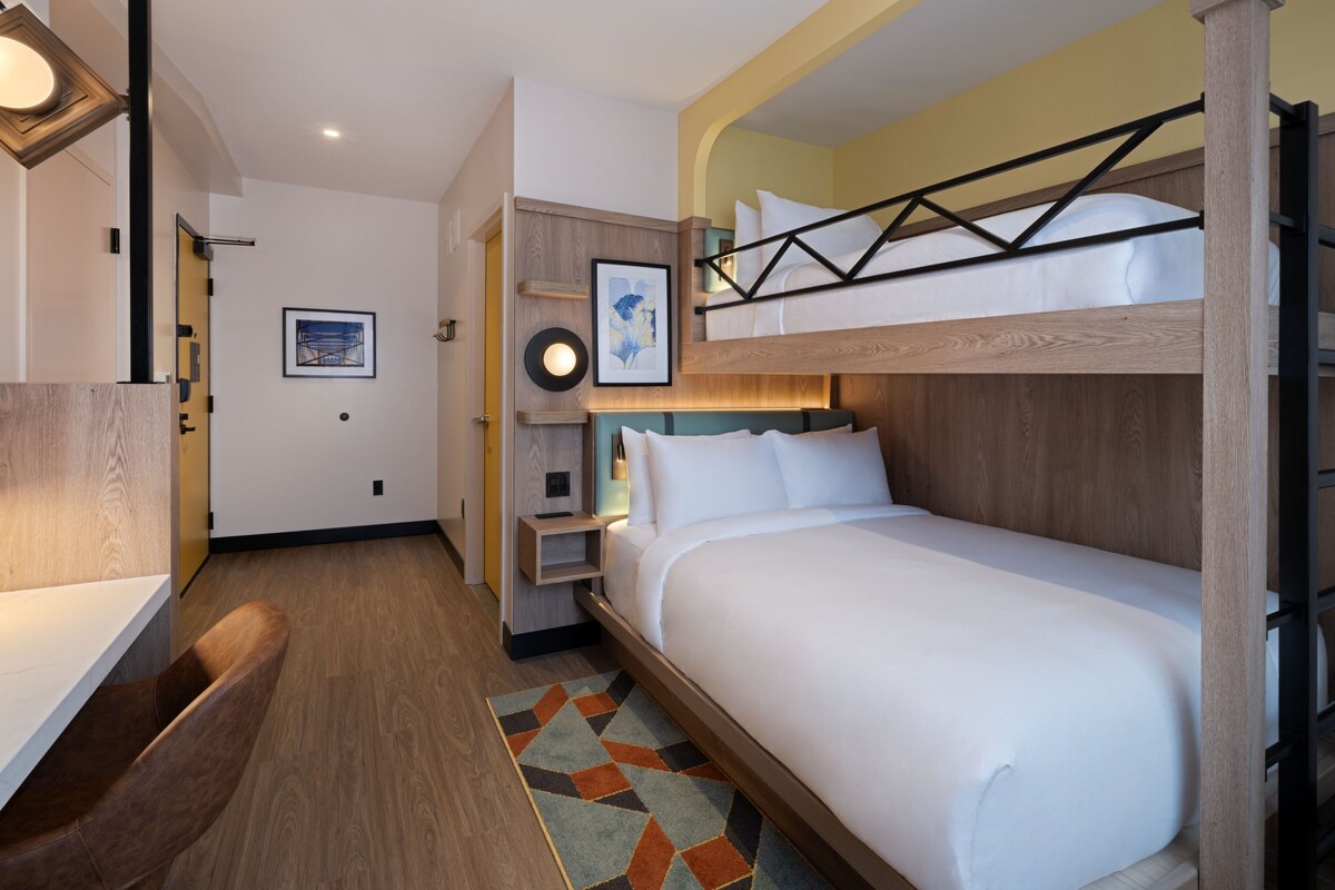 Una habitación de hotel con literas, un escritorio y una pequeña zona de estar.
