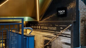 Un interior moderno con una escalera, un panel decorativo azul y una pared que muestra 'VOCO by IHG'.