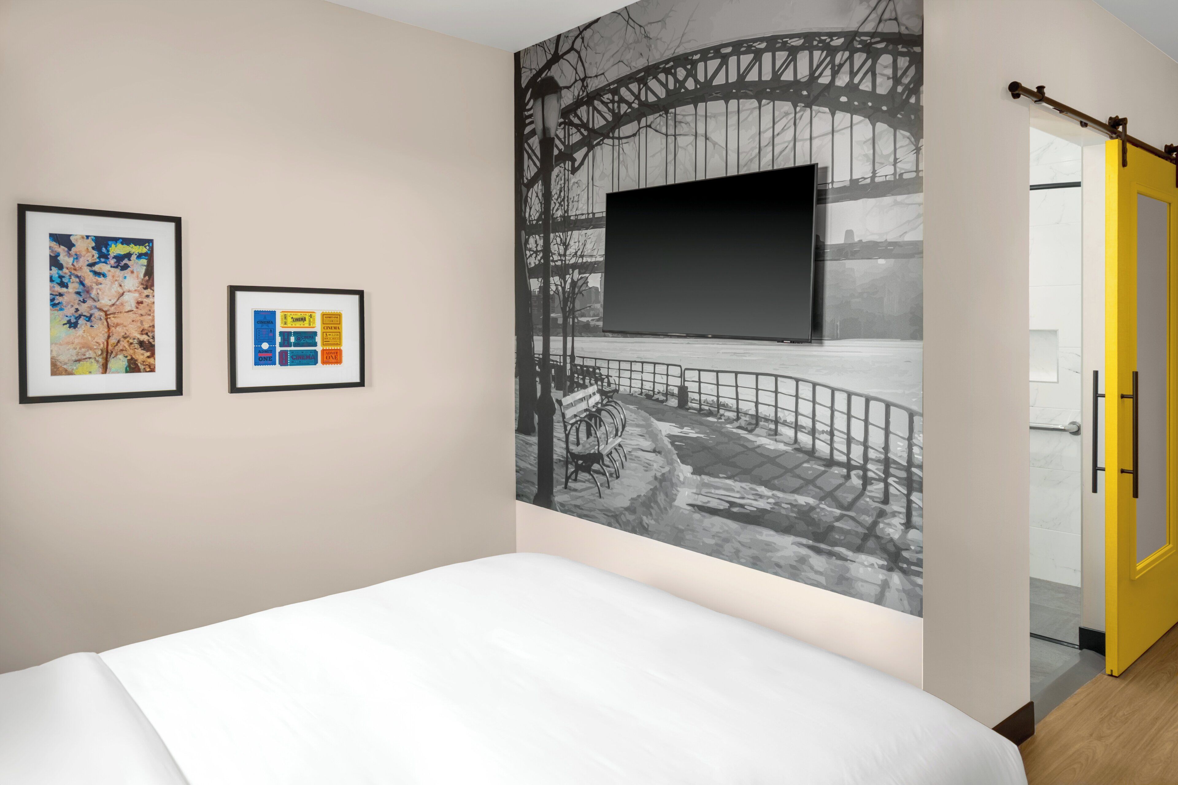 Ein Hotelzimmer mit einem Bett, einer großen Wandmalerei einer Brücke und zwei gerahmten Bildern an der Wand.
